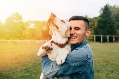 Mutlu genç adam açık havada gün batımında elele köpek Labrador