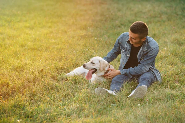 Человек отдыхает со своей собакой Лабрадор на улице — стоковое фото