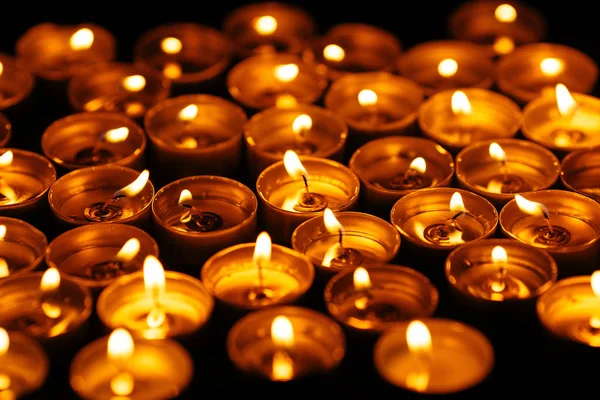Quemando velas. Muchas velas encendidas en la oscuridad - Concepto de luto . —  Fotos de Stock