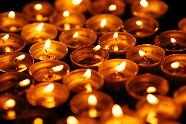 Velas encendidas. Muchas velas queman luz brillante. Velas en la oscuridad - concepto de paz —  Fotos de Stock