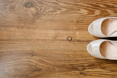 Düğün Bayan aksesuarlar. Ahşap arka plan üzerinde alyans ve krem kadın düğün ayakkabıları.