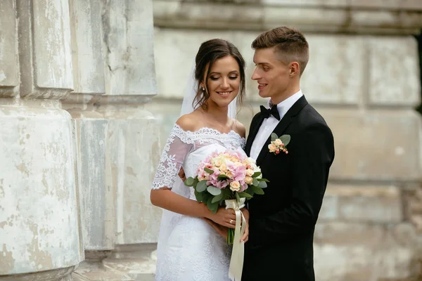 Novia y novio sonriendo cerca de las murallas del castillo. Día de la boda . — Foto de Stock