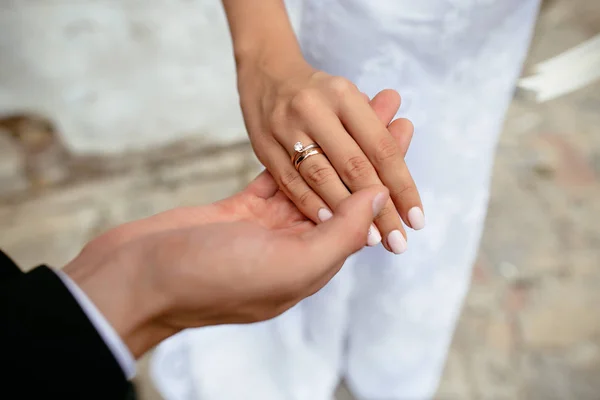 Primer plano de los detalles de la boda. La mano del novio sosteniendo la mano de la novia. El anillo de bodas de la novia en el dedo. Día de la boda . — Foto de Stock