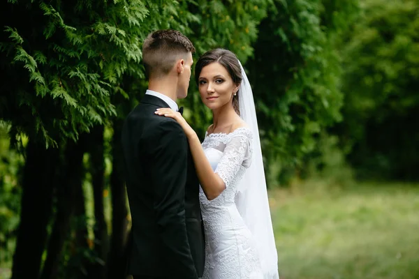 Dia do casamento. Bela noiva e elegante noivo andando no jardim verde após a cerimônia de casamento . — Fotografia de Stock