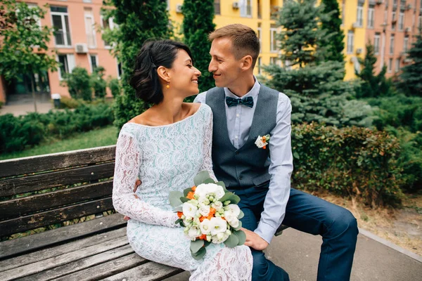 Novia feliz y novio sentado en el banco el día de la boda — Foto de Stock