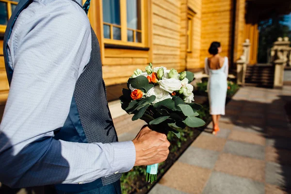 장미 꽃 아름 다운 신부를 위한 웨딩 부케를 들고 신랑 — 스톡 사진