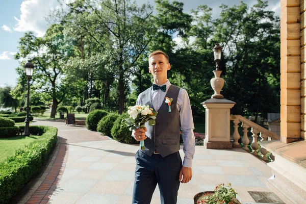 Elegante novio con bouqet de flores de boda en el día de la boda — Foto de Stock