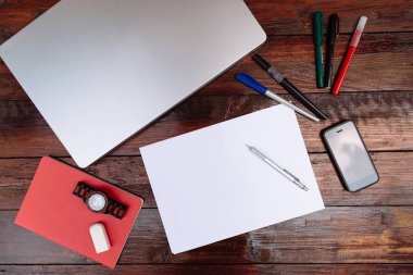 Çalışma alanı, renkli kalem, cep telefonu, dizüstü bilgisayar ve bilek boş sayfaya bir ahşap arka plan üzerinde - izlemek kadar alay