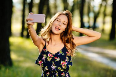 Güzel kız ormanda bir akıllı telefon üzerinde selfie yapar.