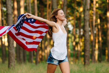 Elinde Amerikan bayrağı ile çalışan kot şortlu kız.