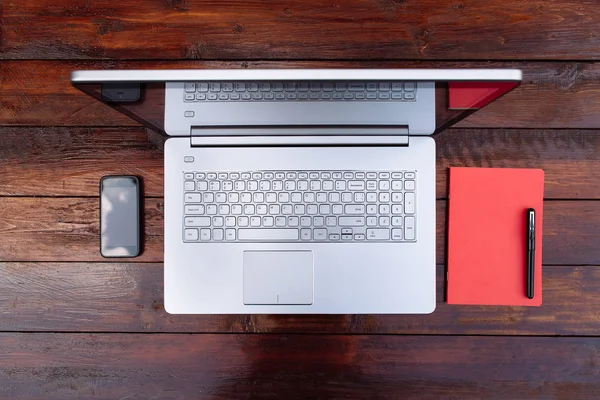 Laptop na stary, drewniany stół z telefonu komórkowego, Notes i długopis. — Zdjęcie stockowe