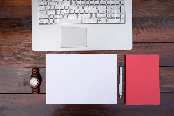 Lugar de trabajo, hoja de papel en blanco con un lápiz y relojes de pulsera y portátil en un escritorio de madera - Mock up — Foto de Stock