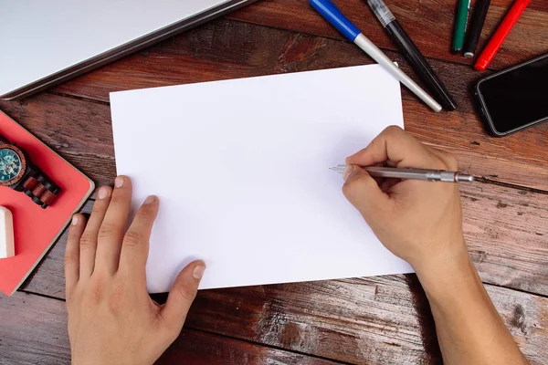 Am Arbeitsplatz zeichnet die Hand auf weißem Blatt. Handzeichnung auf einem leeren Blatt Papier mit Farbstiften auf einem Holztisch - Attrappe — Stockfoto