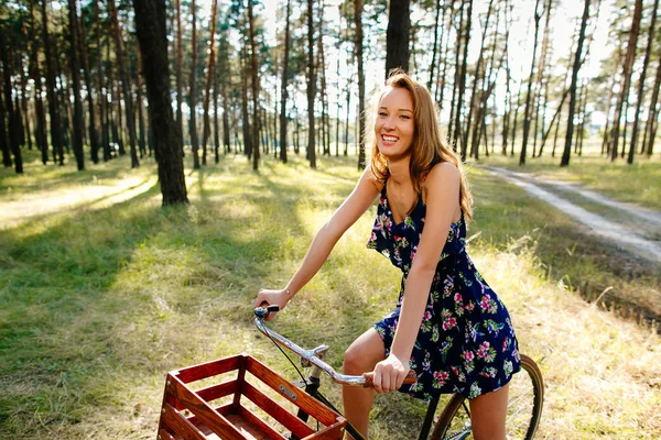 Chica feliz en una bicicleta en el bosque . — Foto de Stock