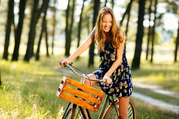 Chica feliz en una bicicleta en el bosque . — Foto de Stock