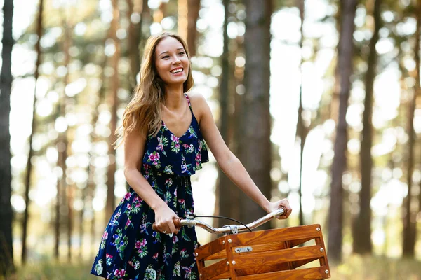 Ευτυχισμένος κορίτσι σε ένα ποδήλατο με ένα καλάθι στο δάσος. — Φωτογραφία Αρχείου