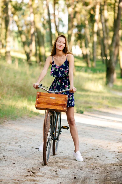Chica feliz en una bicicleta en el bosque . — Foto de Stock