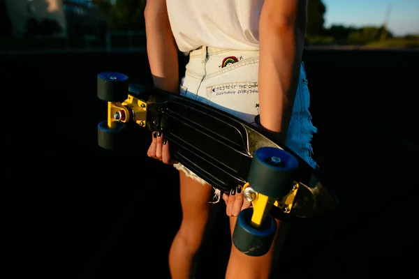 Вид ззаду красива дівчина зі скейтбордом в руках . — стокове фото