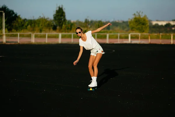 Mooi meisje met haar zonnebril schaatsen op. — Stockfoto