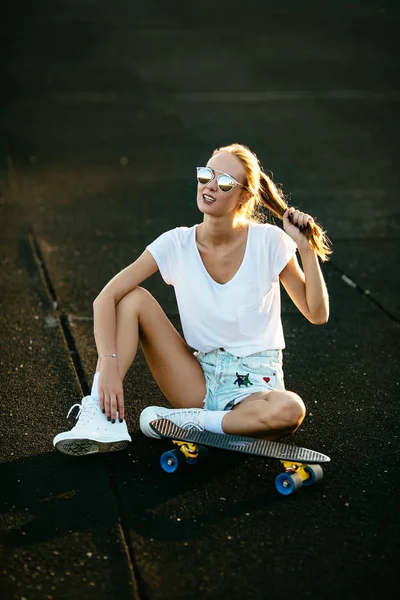 Hezká dívka v černých brýlích oddechuje po skateboarding. — Stock fotografie