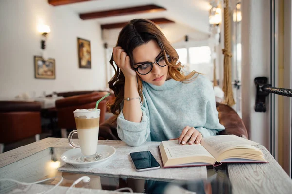 Studente intelligente ragazza che studia in caffè e lettura del libro mentre beve caffè — Foto Stock