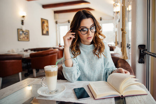 Умная студентка учится в кафе, когда пьет кофе
