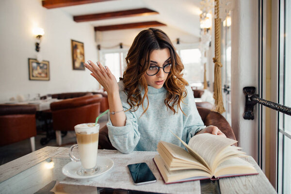 Уставшая студентка готовится к экзаменам в кафе
