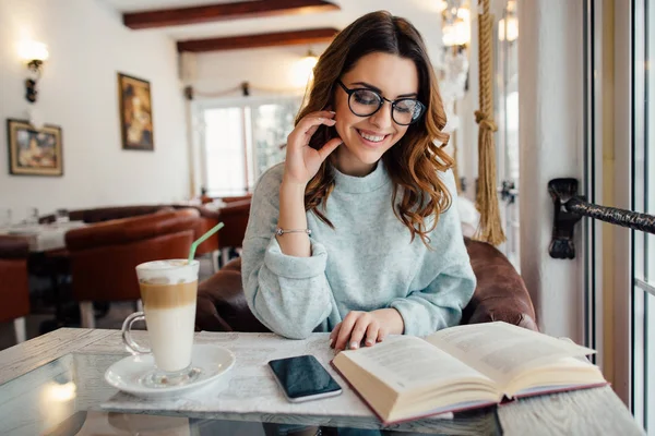 Chica en el café leyendo libro divertido y sonriendo — Foto de Stock