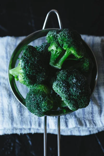 Durkslag av frysta broccolibuketter på duk. — Stockfoto