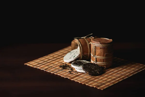 A composição do chá puer chinês embalado em uma esteira de bambu . — Fotografia de Stock