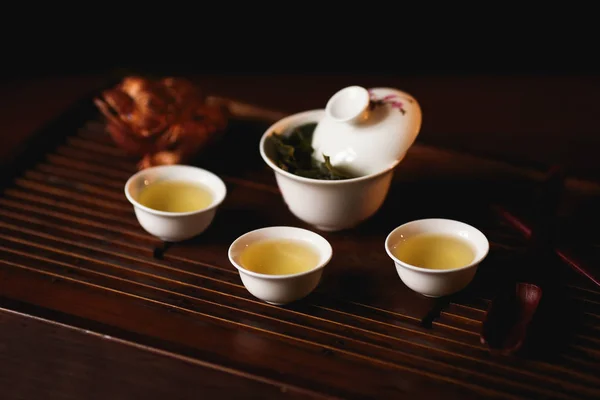 Cérémonie du thé chinois. Gaiwan en porcelaine, trois tasses de thé chinois et grenouille dorée sur le bureau de thé . — Photo