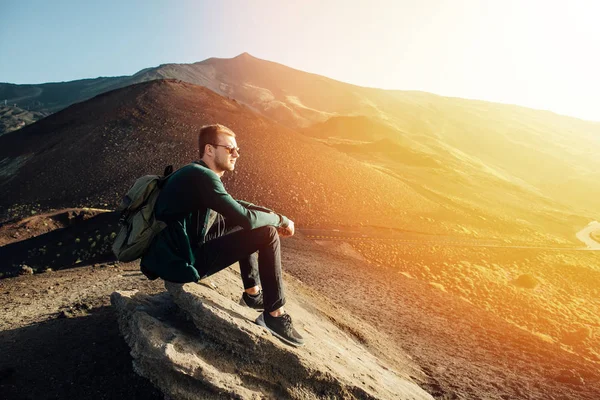 Hombre sentado en la roca al amanecer en el fondo del volcán Etna montaña en Sicilia — Foto de Stock