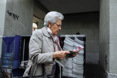 Zürih, İsviçre, 11 Ağustos 2016. Yaşlı kadın kentsel sokak üstünde belgili tanımlık gitmek gazete okuma