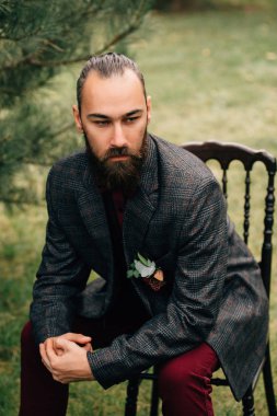Bir sandalyede oturan bir sakallı damat portresi.