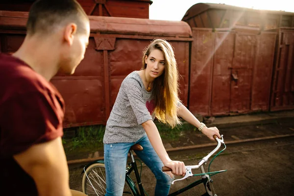 Jovem bela mulher de bicicleta olhando para o namorado . — Fotografia de Stock