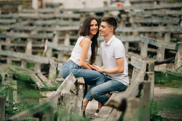 Glada vackra par i kärlek i denim jeans sitter på bänken och leende — Stockfoto