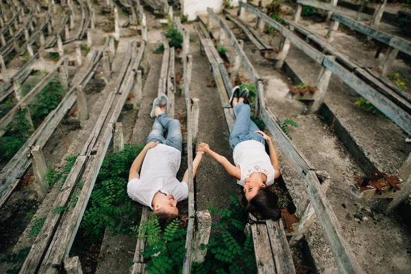 Mooie verliefde paar liggen op Bank buiten hand in hand en kijken naar elkaar — Stockfoto