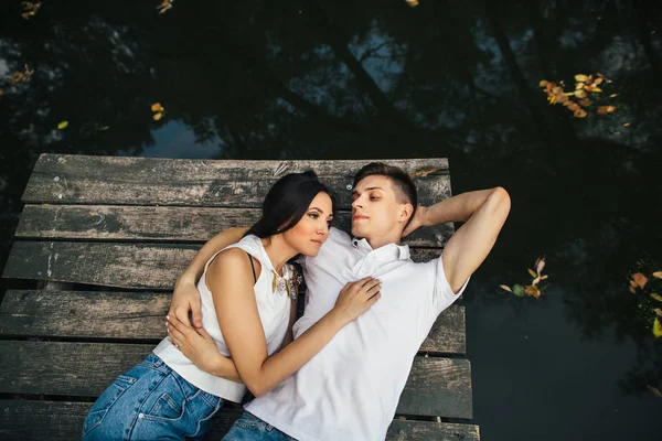 Mooie verliefde paar liggen op oude houten pier op de rivier en genieten van het romantisch moment — Stockfoto