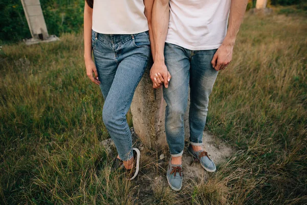 Pareja en el amor en los zapatos de mezclilla y jeans, tomados de la mano al aire libre — Foto de Stock