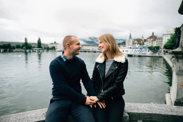 Couple heureux amoureux assis au bord de l'eau avec une belle vue sur le lac et la montagne — Photo