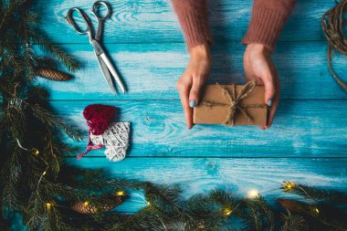 Noel öğeleri bir mavi wodden tablo. Noel hediye sarma kadının elleri.