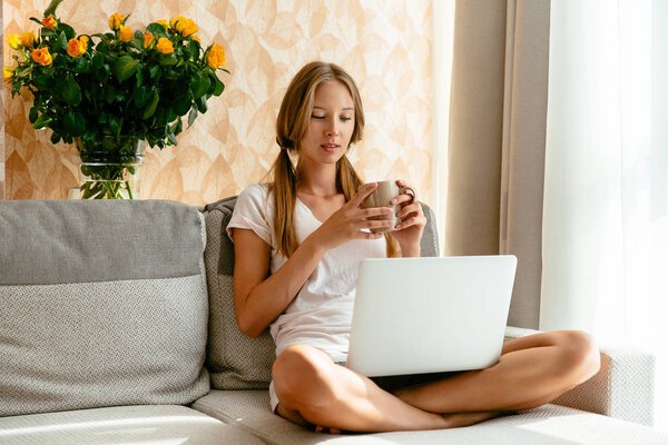 Woman watching TV series on laptop on sofa at home