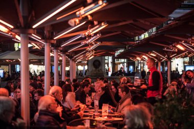 Viyana, Avusturya - 6 Kasım 2019: Bir Viyana Bar Cafe 'nin terasında oturan kalabalık, kışın ısıtılarak kırmızı ışık üreten elektrikli ısıtma sistemi ile ısıtılıyor.