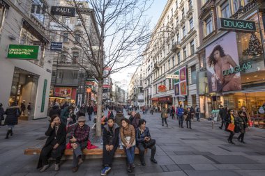 Viyana, Avusturya - 6 Kasım 2019: Viyana şehir merkezinin ana alışveriş caddesi Karntnerstrasse 'de mola verip bir bankta oturan Asyalı turistler