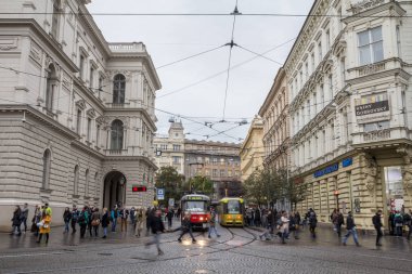 Brno, Çek Cumhuriyeti - 5 Kasım 2019: Jostova caddesini geçmek için acele eden bir grup czech vatandaşı, aynı zamanda Salina veya Dpmb olarak da bilinen yerel toplu taşımacılığa ait raylara ve tramvaylara bakıyorlar.