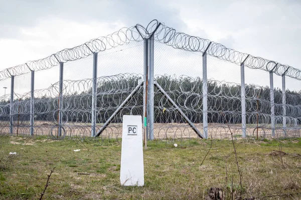 Border fence between Subotica (Serbia) & Kelebia (Hungary) with a boundary marker. This border wall was built in 2015 to stop the incoming refugees & migrants during the refugees crisis, on Balkans Route