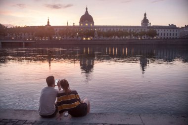 Çiftler, aşıklar, Rhonelar 'ın nehir kıyısında, Quais De Rhone' da, Fransa 'nın Lyon kentindeki ana anıtlara bakan akıllı birine bakıyorlar.