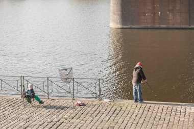 PRAG, CZECHIA - 31 Ekim 2019: Dedesi ve torunu Prag 'ın merkezindeki Vltava nehrinde balık tutuyorlar. Vltava Nehri Çek Cumhuriyeti 'nin başlıca balıkçılık noktalarından biridir.