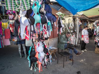 BELGRAD, SERBIA - 9 Ekim 2016: Satıcı arka plandaki malı izlerken, Belgrad Pazarı 'nda durup sutyen, iç çamaşırı ve kadın iç çamaşırı satmak