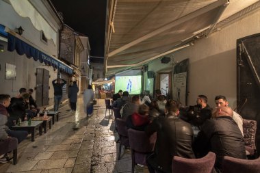 SARAJEVO, BOSNIA - 15 Nisan 2017: Erkekler, Saraybosna şehir merkezinin tipik sehpası olan Bascarsija ilçesinde gece barlarda ve kafelerde oturup futbol maçı izliyor